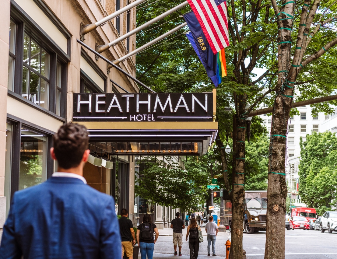 man walking down the street towards Heathman Hotel entrance